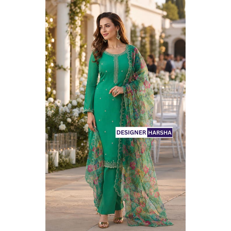 Puede incluir: Un conjunto de t&uacute;nica verde esmeralda de manga larga y pantal&oacute;n a juego con delicados bordados plateados en el cuello y el dobladillo. Un dupatta ligero y transparente con estampado floral colorido cuelga del hombro. El texto dice DESIGNER HARSHA.
