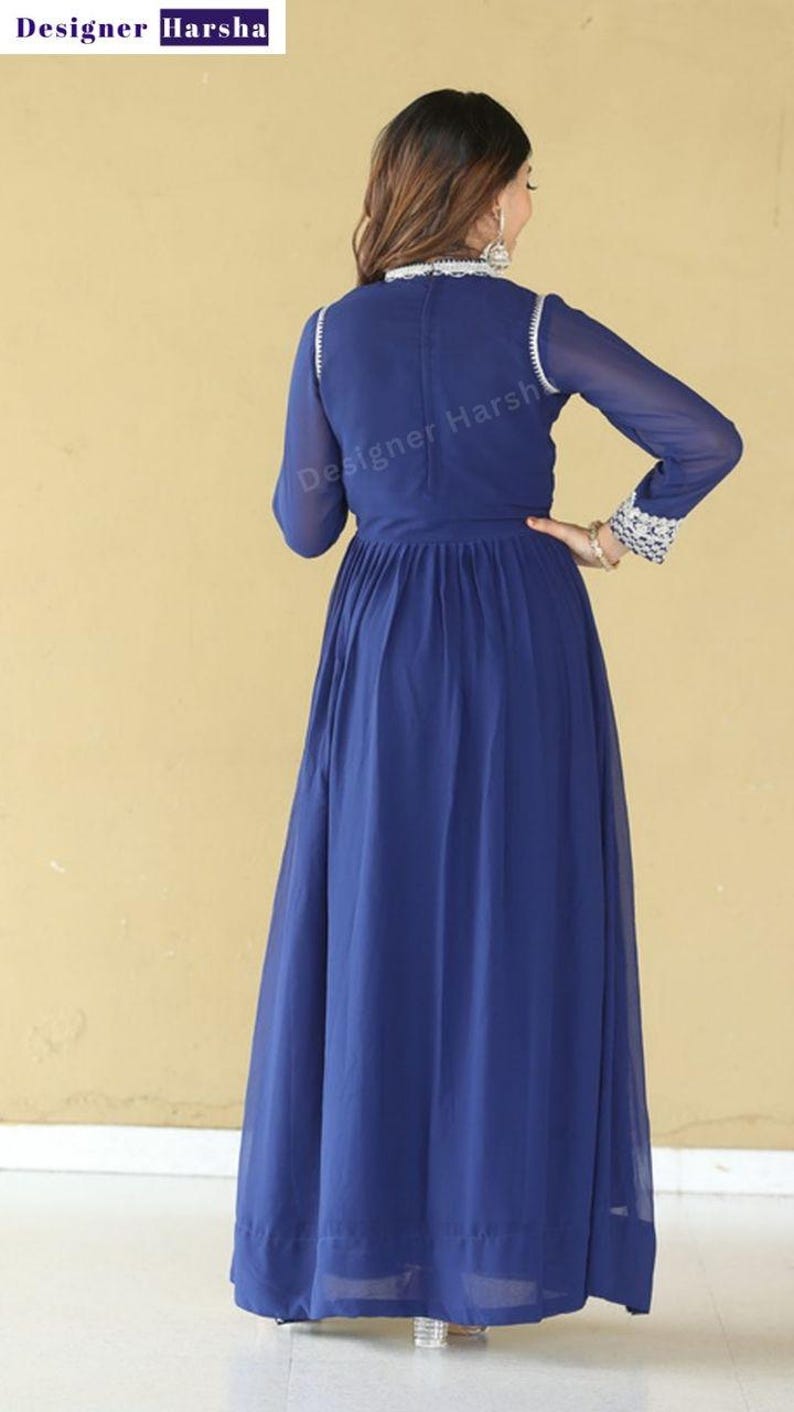 May include: A long, royal blue maxi dress with a high neckline and long sleeves. The dress has a gathered waist and a flowing skirt. The dress is decorated with silver embroidery around the neckline and cuffs.