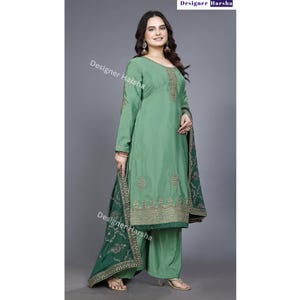 May include: A green salwar kameez with gold embroidery. The kameez has long sleeves and a round neckline. The salwar is a pair of wide-legged pants. The dupatta is a long scarf with a green and gold border.