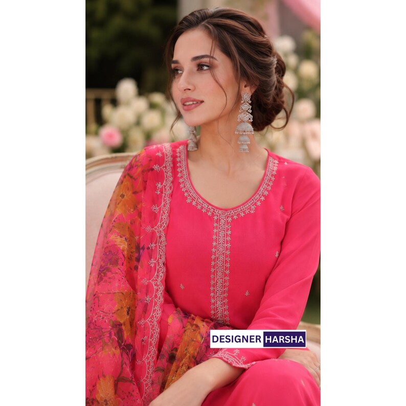 Puede incluir: Una t&uacute;nica de color rosa brillante de manga larga con intrincados bordados plateados a lo largo del escote y el panel central, combinada con una dupatta floral transparente a juego en tonos rosa, naranja y amarillo. El texto DESIGNER HARSHA es visible.