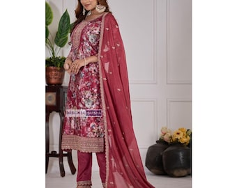 May include: A burgundy floral print salwar kameez set. The ensemble includes a long tunic, matching pants, and a sheer dupatta. The tunic features intricate embroidery around the neckline and hem. The text "DESIGNER HARSHA" is visible on the garment.