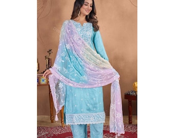 Puede incluir: Un conjunto salwar kameez azul claro con intrincados bordados blancos en el escote, los puños y el dobladillo. El atuendo incluye pantalones a juego y una dupatta transparente en tonos de azul, morado y blanco. La dupatta tiene delicados estampados florales y borlas.