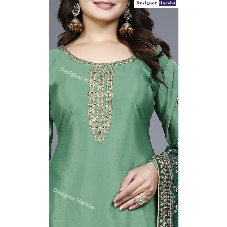 May include: A green salwar kameez with gold embroidery on the neckline. The fabric is a smooth, silky material. The salwar kameez is a traditional Indian garment.