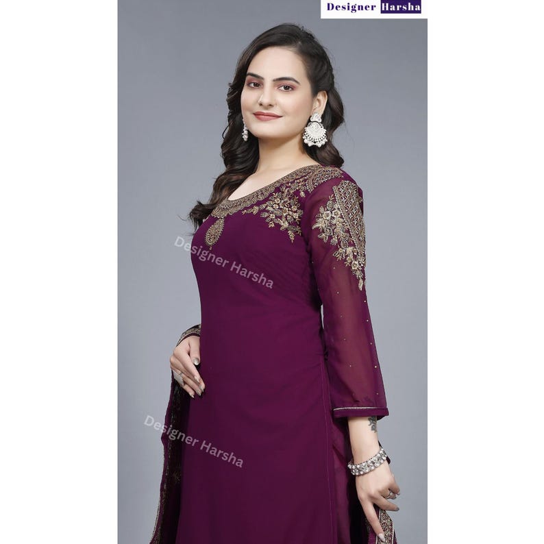 Puede incluir: Una mujer lleva un vestido largo de manga larga de color morado con bordados dorados. El vestido tiene un escote redondo y una silueta ajustada. La mujer est&aacute; de pie frente a un fondo blanco.