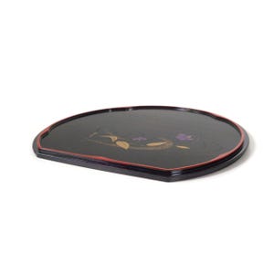 May include: A black, semi-circular wooden tray with a red trim. The tray features a floral design in gold and purple. The tray is likely used for serving or display purposes.