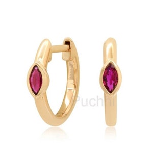 May include: A pair of gold hoop earrings with a small, marquise-shaped ruby gemstone set in each hoop.