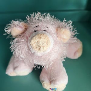 May include: Pink plush pig toy with a fuzzy texture. The pig has a small, light brown snout and a Webkinz tag on its foot.