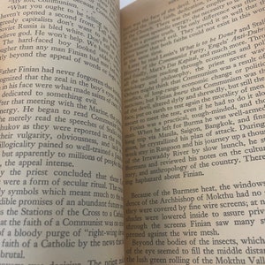 May include: Open book pages with printed text. The text is in black ink on aged, off-white paper. The book is open, revealing two facing pages with multiple paragraphs of text. The pages are slightly angled.