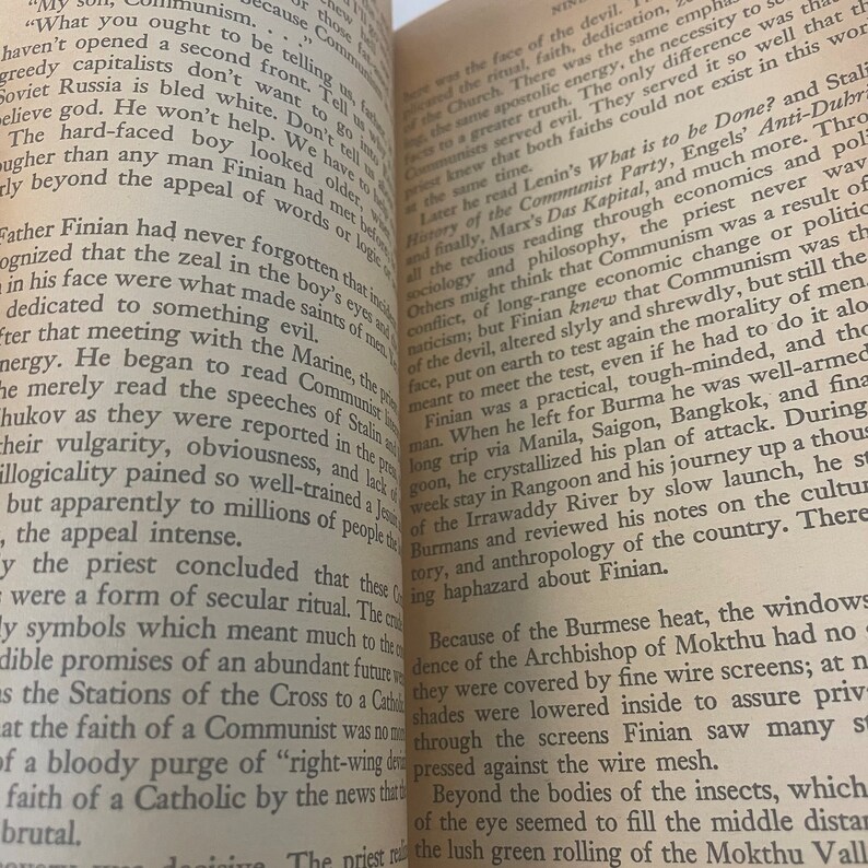 May include: Open book pages with printed text. The text is in black ink on aged, off-white paper. The book is open, revealing two facing pages with multiple paragraphs of text. The pages are slightly angled.
