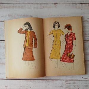 Puede incluir: Un libro antiguo abierto con tres ilustraciones de conjuntos. La página izquierda muestra un conjunto de chaqueta y falda marrón texturizado. La página derecha muestra un vestido amarillo estampado y un traje de falda rojo con lunares y bolso.