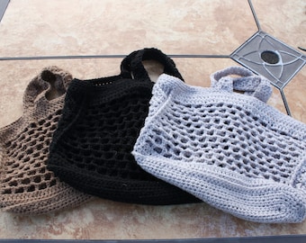 Puede incluir: Tres bolsas de malla de crochet en marrón, negro y gris. Las bolsas están hechas con un patrón simple y abierto y tienen un solo asa de bucle.
