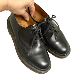 May include: Black leather lace-up shoes with a Dr. Martens logo on the insole.