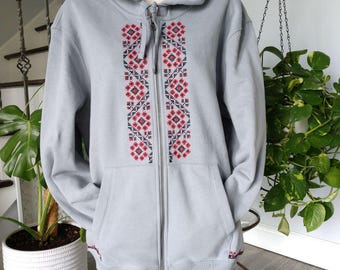 Peut inclure: Un sweat à capuche bleu clair avec un motif brodé rouge et noir sur le devant.