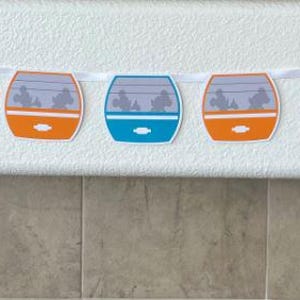 May include: A colourful banner with a string of paper cutouts shaped like a train car. The train cars are in shades of purple, red, green, orange, blue, and green. Each car has a window with a silhouette of people inside.