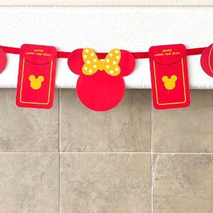 Puede incluir: Guirnalda de papel roja y amarilla con personajes de Mickey Mouse y Minnie Mouse, linternas y rollos. La guirnalda dice "Feliz A&ntilde;o Nuevo Lunar" y "2023".