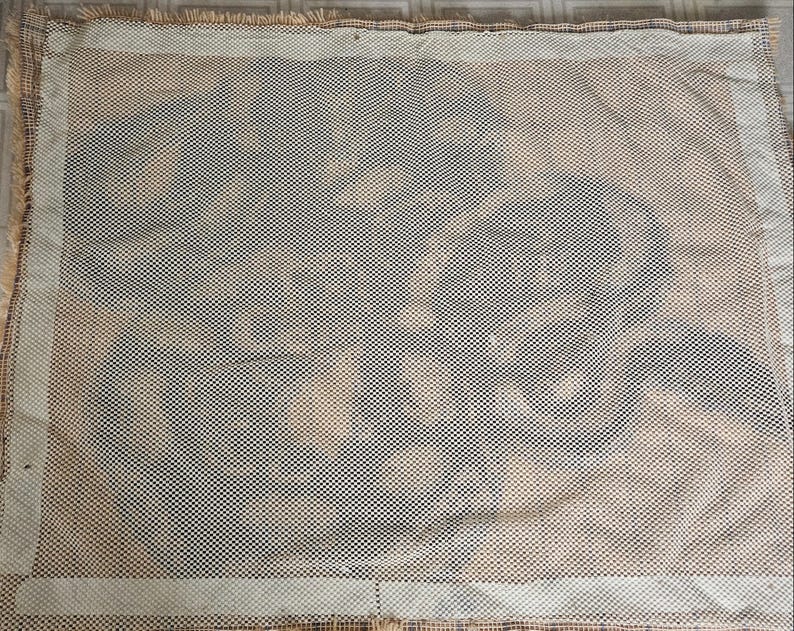May include: A close-up of a beige canvas with a white mesh pattern. The canvas is slightly wrinkled and has a frayed edge.