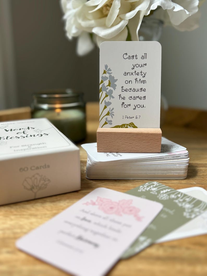 May include: A set of "Words of Blessings" cards with a wooden card holder. The cards have floral designs and inspirational quotes. The text on the displayed card reads "Cast all your anxiety on him because he cares for you."