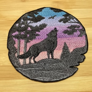 May include: Embroidered patch featuring a howling wolf silhouette against a colorful sunset sky. The design includes trees and a flying bird, with a black border. The patch is circular and suitable for jackets, bags, or other fabric items.
