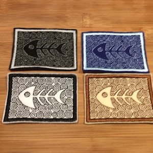 Peut inclure: Quatre écussons brodés avec un motif d'arête de poisson. Chaque écusson rectangulaire a une bordure contrastée et un motif de fond tourbillonnant. Les arêtes de poisson sont noires, blanches ou beiges, sur des fonds noirs, bleus, argentés et beiges.