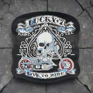 May include: Black embroidered biker patch with the text "LUCKY 7" and "BIKES BROADS USA". The patch features a skull, a motorcycle, and the words "LIVE TO RIDE" and "EST. 1903".