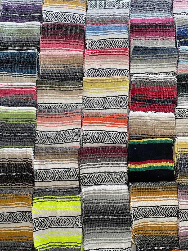 May include: A collection of colorful Mexican blankets with various patterns and stripes. The blankets are made of woven wool and are arranged in a grid pattern.