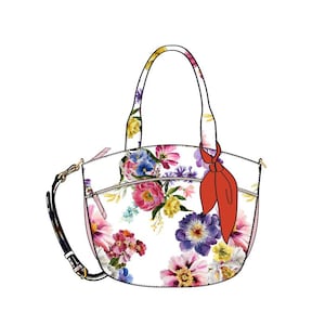Könnte beinhalten: Eine weiße Handtasche mit Blumenmuster und einer roten Schleife. Die Tasche hat einen Henkel oben und einen Schultergurt.