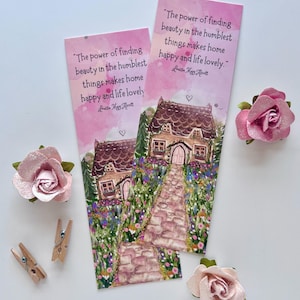 May include: Two pink watercolor bookmarks with a house illustration and the quote "The power of finding beauty in the humblest things makes home happy and life lovely." Decorative pink paper roses and wooden clothespins are also present.