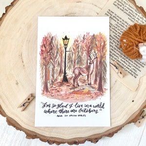 May include: A watercolor illustration of a deer standing in a forest with a streetlight in the background. The quote "I'm so glad I live in a world where there are Octobers." by Anne of Green Gables is written below the image.
