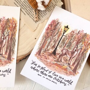 May include: A watercolor illustration of a deer walking through a forest with a street lamp in the background. The quote "I'm so glad I live in a world where there are Octobers." is written below the image, attributed to Anne of Green Gables.
