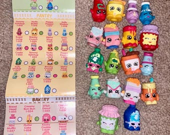 May include: A collection of colorful Shopkins figures, each with unique designs and expressions. The image includes a checklist with names like "Tommy Ketchup" and "Creamy Bun-Bun".