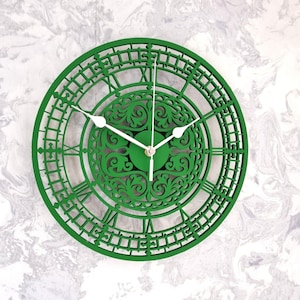 May include: A green wall clock with Roman numeral markings and a decorative, intricate design. The clock has white hands and a gold centre.