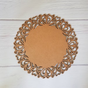 May include: A brown wooden round charger plate with a decorative lace design. The plate has a smooth, unfinished surface.