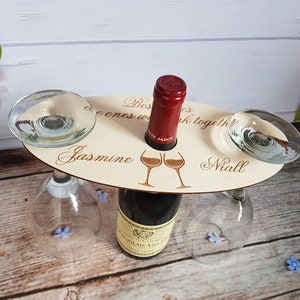 May include: Wooden wine bottle holder with two glass holders. The holder has the text "Best friends are the ones we drink together" with the names "Jasmine" and "Niall" engraved on it.