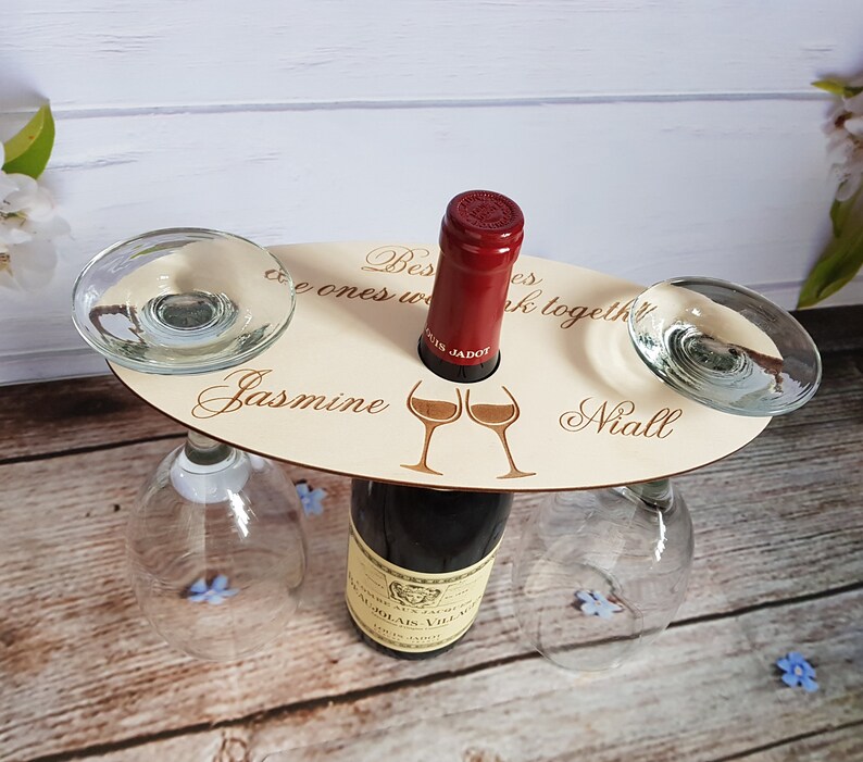 May include: Wooden wine bottle holder with two glass holders. The holder has the text "Best friends are the ones we drink together" with the names "Jasmine" and "Niall" engraved on it.