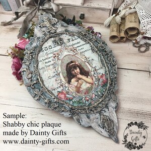 Pode incluir: Uma placa de madeira branca desgastada com uma moldura decorativa ornamentada. A placa apresenta um an&uacute;ncio vintage com uma menina em um vestido rosa e o texto "FIL Nombreus comhendes SERRATIO JURY ARSEILL UX EXPOSITE HORS C AUX EXPOSIC Da Co 9,1 JSINES AUX".