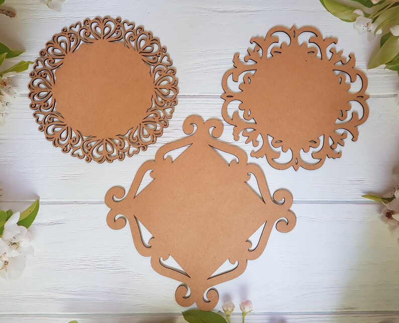 May include: Three decorative wooden plaques with intricate cut-out designs. The plaques are brown and have a circular and square shape.