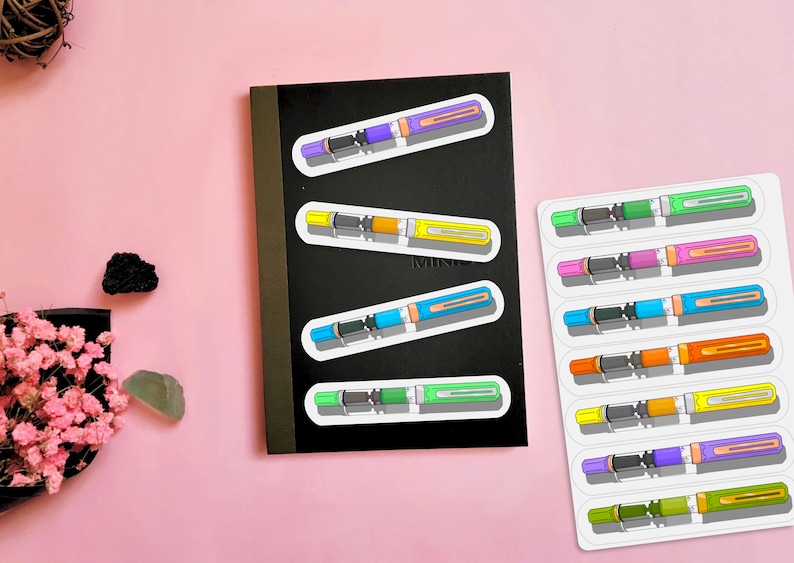 May include: A sheet of colorful fountain pen stickers. The stickers are arranged in rows on a white background. Each sticker features a different color pen with a black ink cartridge and a gold trim. The stickers are perfect for adding a touch of personality to notebooks, laptops, and other surfaces.