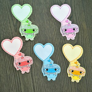 May include: Six colorful heart-shaped note cards with a cartoon character holding a balloon. Each card features a different character with a different colored balloon and heart.