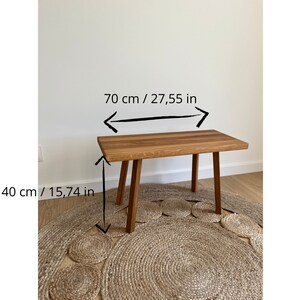 May include: A rectangular wooden bench with four straight legs. The bench features a natural wood grain finish. Text on the image indicates a length of 27.55 inches and a height of 15.74 inches, providing clear dimensions for this furniture piece.