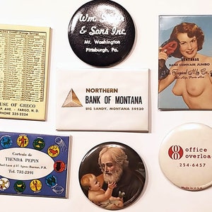 May include: A collection of vintage advertising buttons and magnets. The buttons feature a variety of designs, including a bank, a store, a business, and a religious figure. The magnets feature a woman in a swimsuit, a zodiac chart, and a business logo.