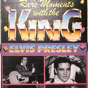May include: VHS video cassette cover featuring Elvis Presley with the title "Rare Moments with the King". The cover has a collage of four black and white photos of Elvis Presley. The text "An Historic Documentary of Rare Interviews, News Films, TV Clips, Comedy Bits and More." is printed on the bottom of the cover. The text "This film collection is not authorized by the Presley estate or any other entity." is printed below the documentary description. The Goodtimes logo is printed in red and white on the bottom left corner of the cover. The VHS logo is printed in white on the bottom right corner of the cover.