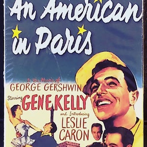 May include: A VHS tape cover for the musical film "An American in Paris" starring Gene Kelly and Leslie Caron. The cover features a colourful image of the actors and the Eiffel Tower. The text "to the music of George Gershwin" is also included.