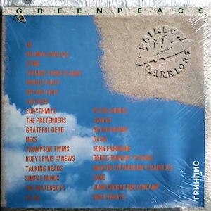 Peut inclure: Une pochette d'album vinyle bleu et blanche avec le texte "GREENPEACE" et "RAINBOW WARRIORS" en cercle. L'album présente une liste d'artistes dont Belinda Carlisle, Sting, Terence Trent D'Arby, World Party, Bryan Ferry, Lou Reed, Eurythmics, The Pretenders, Grateful Dead, INXS, Thompson Twins, Huey Lewis and the News, Talking Heads, Simple Minds, The Waterboys, Peter Gabriel, Aswad, Bryan Adams, Basia, John Farnham, Bruce Hornsby & The Range, Martin Stephenson & The Daintees, Sade, John Cougar Mellencamp et Dire Straits.
