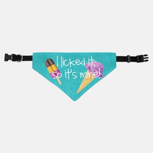 May include: A turquoise blue dog bandana with a white ice cream cone and popsicle graphic. The bandana has the text "I licked it, so it's mine!" printed on it.