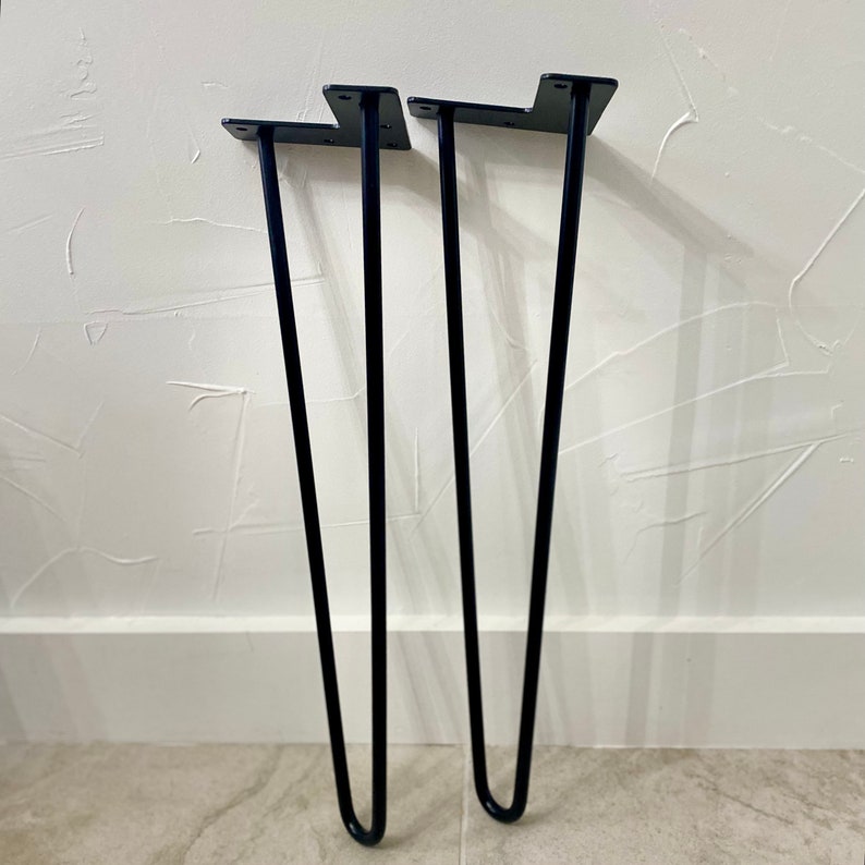 Op de afbeelding: Drie zwarte metalen haarspeldpoten voor meubels. De poten zijn ongeveer 30 cm hoog en hebben een eenvoudig, modern ontwerp.