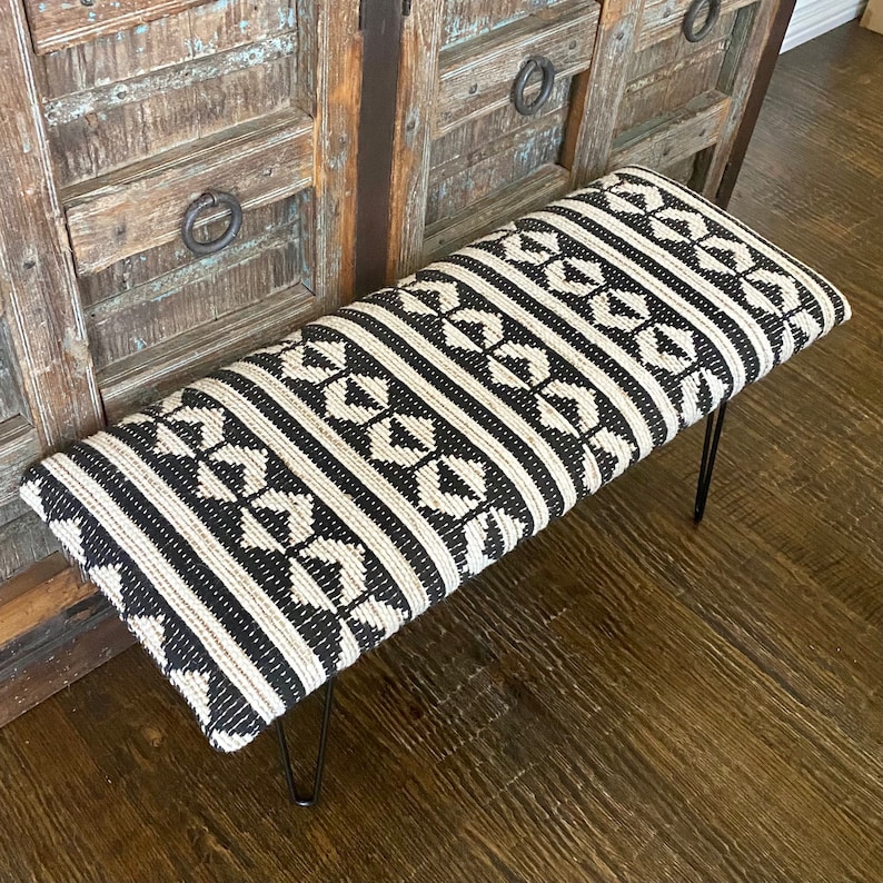 Puede incluir: Un banco con estampado en blanco y negro con un asiento de tejido tejido y patas de horquilla negras.