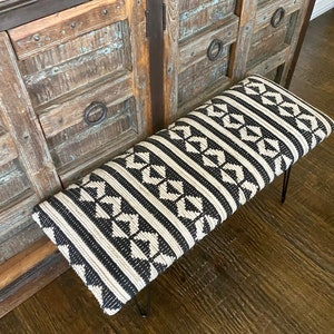 Puede incluir: Un banco con estampado en blanco y negro con patas de horquilla de metal negro. El banco est&aacute; hecho de una tela tejida con un dise&ntilde;o geom&eacute;trico.