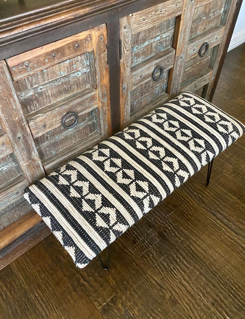 Puede incluir: Un banco con estampado en blanco y negro con patas de horquilla de metal negro. El banco est&aacute; hecho de una tela tejida con un dise&ntilde;o geom&eacute;trico.