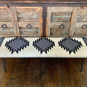May include: A white bench with a black and gray geometric pattern. The bench has black metal hairpin legs.
