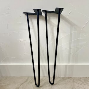 Puede incluir: Tres patas de metal negro en forma de horquilla para muebles. Las patas miden aproximadamente 30 cm de alto y tienen un dise&ntilde;o simple y moderno.